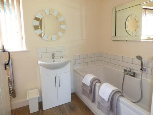 uma casa de banho com um lavatório, uma banheira e um espelho. em Berringtons Barn em Lockleywood