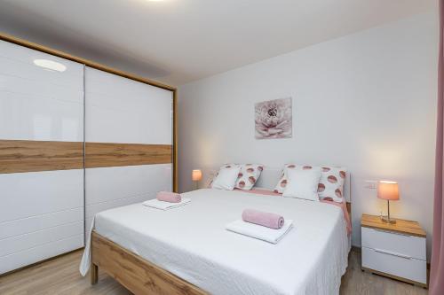 a bedroom with a large white bed with pink pillows at Holiday House Sunset in Bale