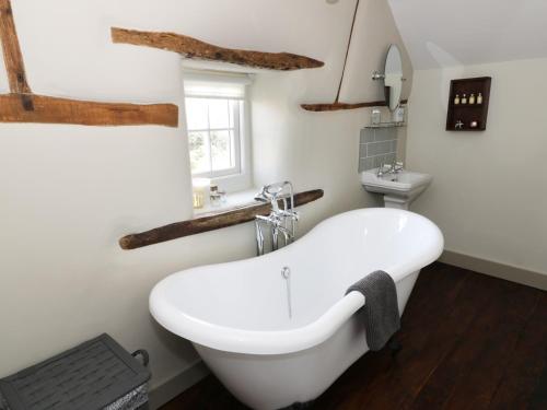 a bathroom with a white tub and a sink at Ivy Cottage in Great Malvern
