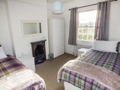 a bedroom with two beds and a fireplace at 1 Willow Cottage in Upton upon Severn