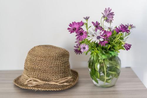 a vase of purple flowers and a hat on a table at Villa La Pagaia Sorrento Coast in Vico Equense