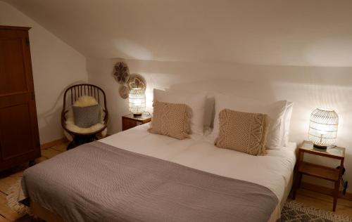 a bedroom with a white bed with two lamps and a chair at St Anton 365 in Sankt Anton am Arlberg