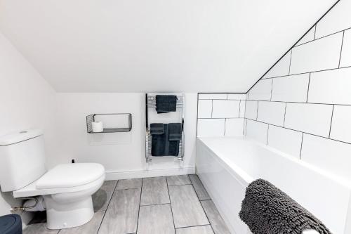 a white bathroom with a toilet and a bath tub at Large Modern 2 Bedroom Queen Street Apartment in Norwich