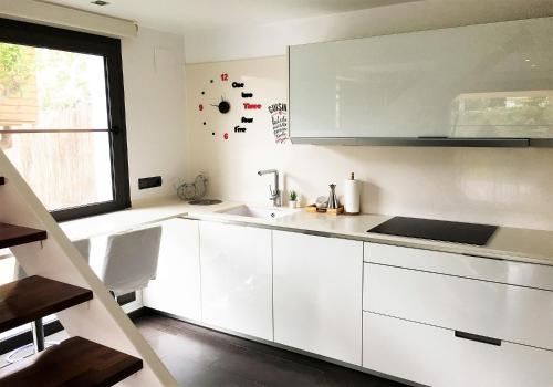 a kitchen with white cabinets and a sink and a window at Villa Rufol in Deltebre