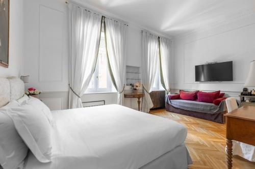 a white bedroom with a bed and a couch at Relais Donna Lucrezia in Rome