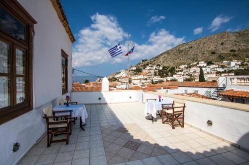 a patio with tables and chairs on a building at Achilleas Apartment in Hydra