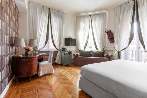 a bedroom with a bed and a desk and curtains at Relais Donna Lucrezia in Rome