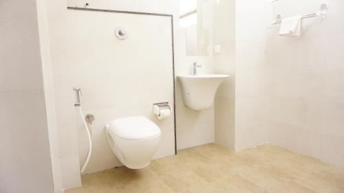 a white bathroom with a toilet and a sink at DayOne Suites in Bangalore