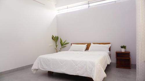 um quarto branco com uma cama com lençóis e almofadas brancos em DayOne Suites em Bangalore