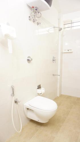 a white bathroom with a toilet and a shower at DayOne Suites in Bengaluru