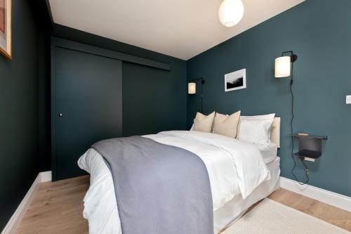 a bedroom with blue walls and a white bed at Norman Road- Brand new luxury GF Apartment in St. Leonards
