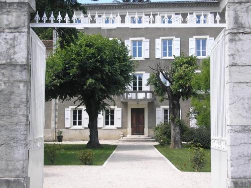an archway leading to a large house with trees at La Saudade in Saint-Péray