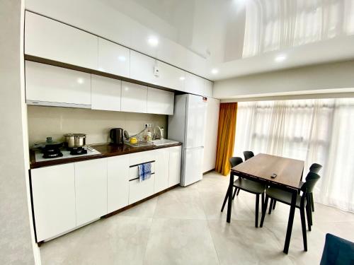 a kitchen with white cabinets and a table and chairs at GSS - A Apartment in Tbilisi City