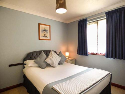 Saint CleerにあるChy Lowennaのベッドルーム1室(青いカーテン付きの大型ベッド1台付)