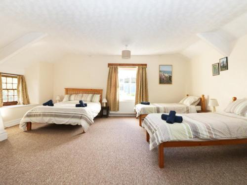 1 dormitorio con 2 camas y ventana en Westroose Farm House, en Otterham