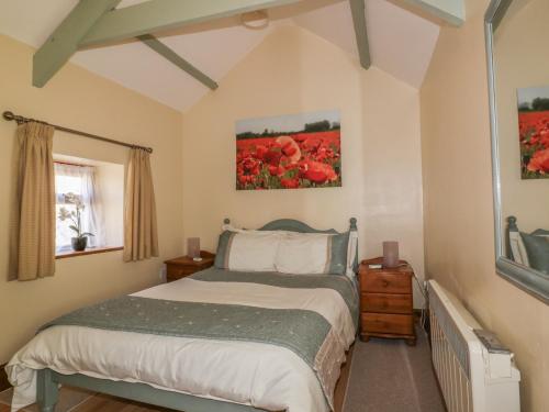a bedroom with a bed and red flowers at Cosy Cottage in Liskeard