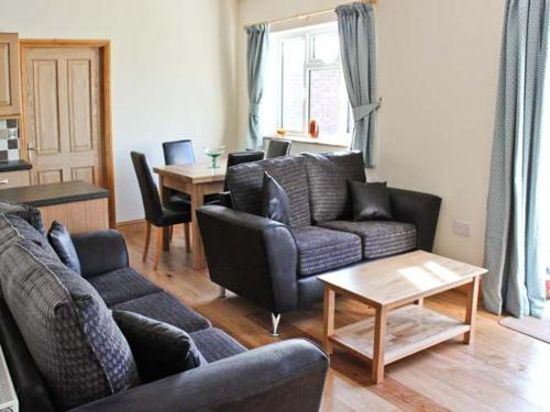 a living room with a couch and chairs and a table at Moat Farm Cottage in Wood Dalling