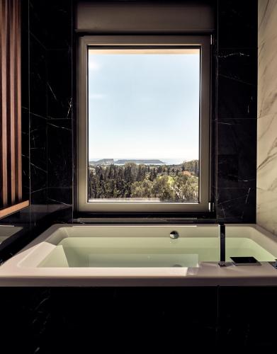 a bath tub in a bathroom with a window at Alexandra SeaView Luxurious Villa, By ThinkVilla in Vasilikos