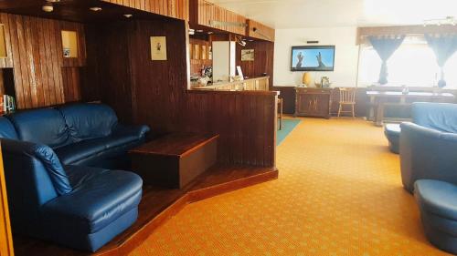 a living room with blue leather furniture and a kitchen at Hotel Hermitage in Sestriere