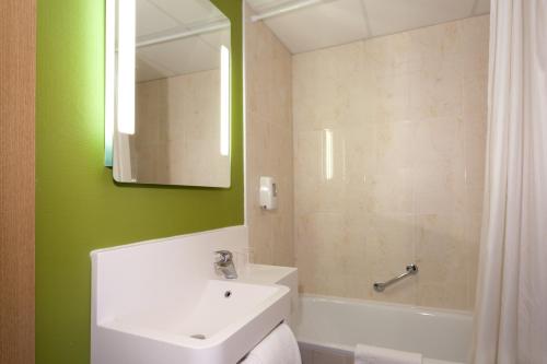 a bathroom with a white sink and a green wall at B&B HOTEL Nîmes Ville Active, parking sécurisé gratuit in Nîmes