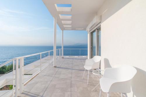 a balcony with white chairs and a view of the ocean at Epipleon suites in Áyioi Apóstoloi