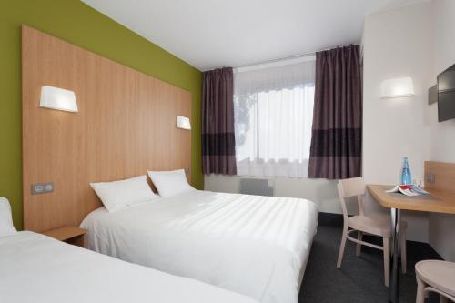 een hotelkamer met 2 bedden en een bureau bij B&B HOTEL Nîmes Ville Active, parking sécurisé gratuit in Nîmes