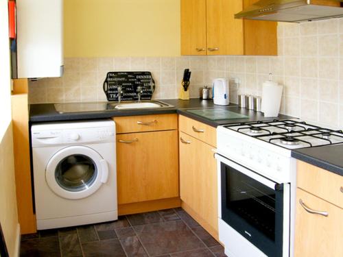 a kitchen with a stove and a washing machine at Drummer Cottage in Loftus