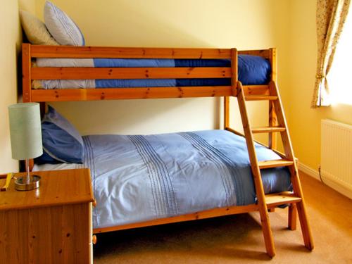 a bedroom with two bunk beds and a desk at Drummer Cottage in Loftus