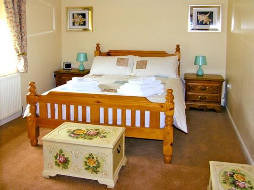a bedroom with a wooden bed and two night stands at Drummer Cottage in Loftus