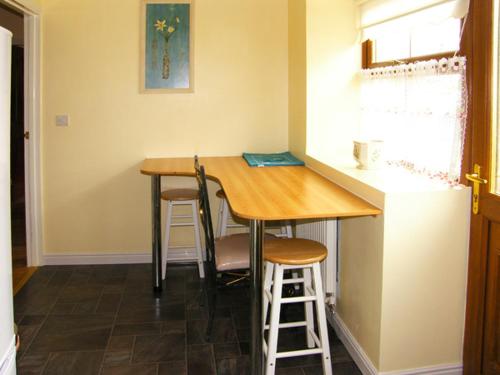 a small kitchen with a wooden table and stools at Drummer Cottage in Loftus