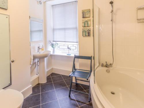 y baño con lavabo, bañera y silla. en The Old Exchange, en Corbridge