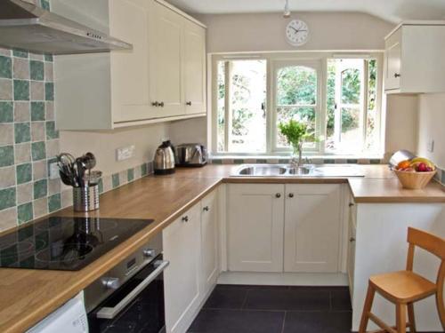 a kitchen with white cabinets and a sink and a window at The Generals Cottage in Mitchel Troy