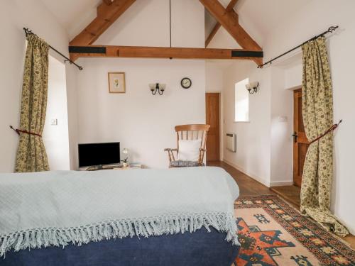 a bedroom with a large bed and a tv at High Park Barn in Uffculme