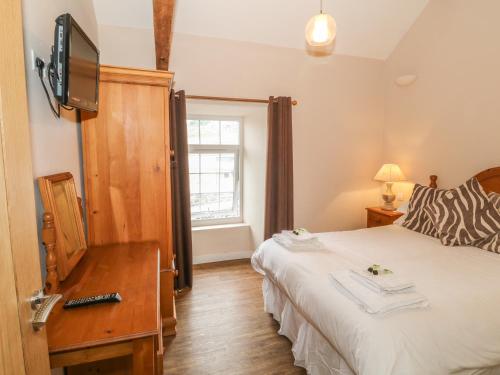 a bedroom with a bed and a tv on the wall at Hen Blas in Aberdaron