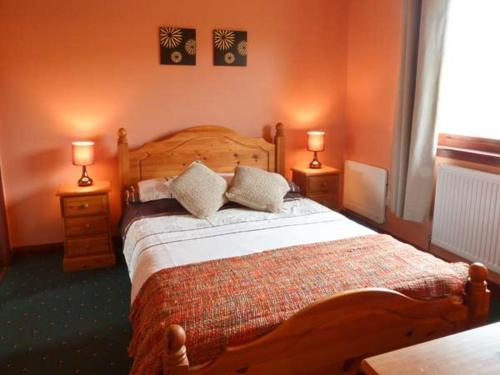 a bedroom with a wooden bed with two lamps on two tables at Ardmore in Trumpan