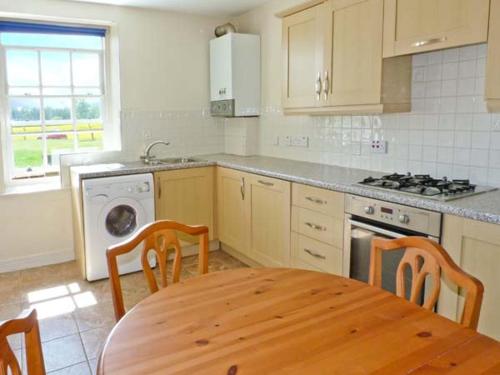 a kitchen with a wooden table and a table and chairs at Kennels Cottage in Saint Boswells