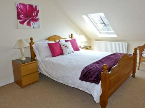 ein Schlafzimmer mit einem großen Bett mit rosa und weißen Kissen in der Unterkunft Kennels Cottage in Saint Boswells