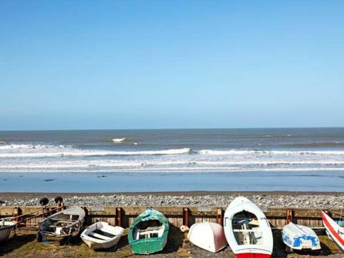 a group of boats are lined up on the beach at Trysor Y Mor in Borth