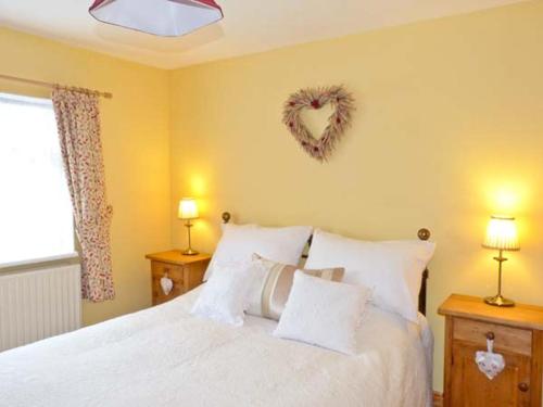 a bedroom with a bed with a heart wreath on the wall at 3 Apsley Cottages in Chartham