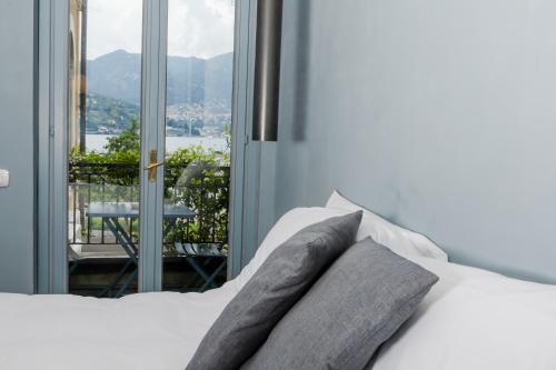 a white bed with pillows and a window with a view at Bello!Lake Como Suites in Como