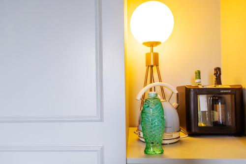 a green vase sitting on a table next to a microwave at Bello!Lake Como Suites in Como