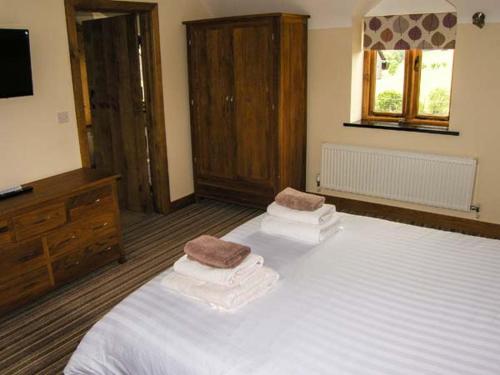 a bedroom with a bed with two towels on it at Tyn Y Celyn Canol in Clocaenog