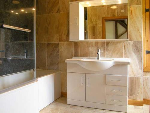 a bathroom with a sink and a tub and a mirror at Tyn Y Celyn Canol in Clocaenog