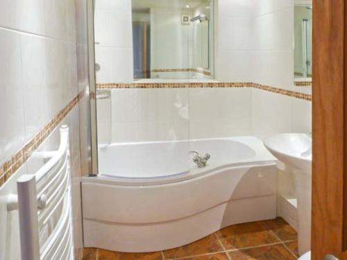 Baño blanco con bañera y lavamanos en Walker's Retreat, en Ambleside