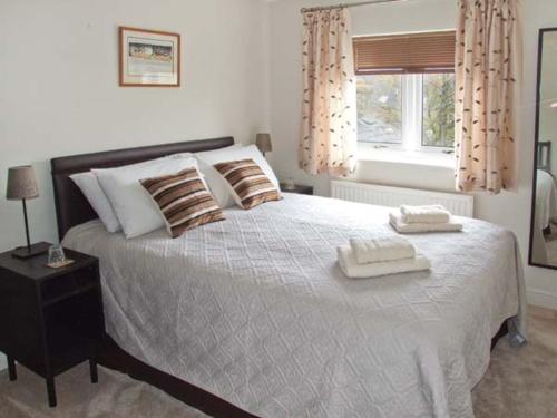 a bedroom with a large bed with two towels on it at Hour Cottage in Stow on the Wold