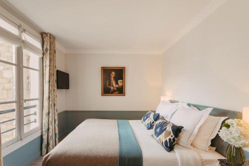 a bedroom with a bed with pillows and a window at Hôtel d'Orsay - Esprit de France in Paris