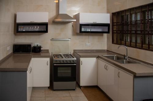 a kitchen with white cabinets and a stove and a sink at RESIDENCE IVOIRE in Accra