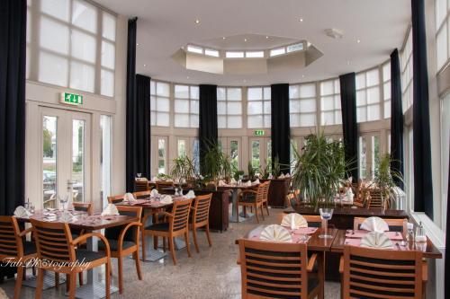 uma sala de jantar com mesas, cadeiras e janelas em Hotel 2000 Valkenburg em Valkenburg