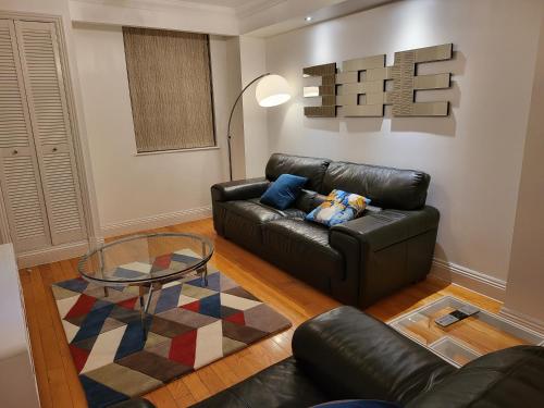 a living room with a leather couch and a glass table at Garland Stylish 2 Bedroom Apartment A Minute Walk From Station in London