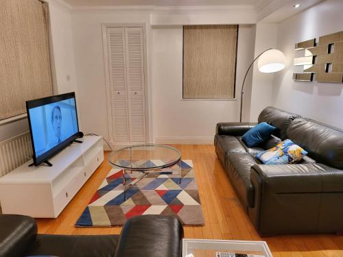 a living room with a couch and a tv at Garland Stylish 2 Bedroom Apartment A Minute Walk From Station in London
